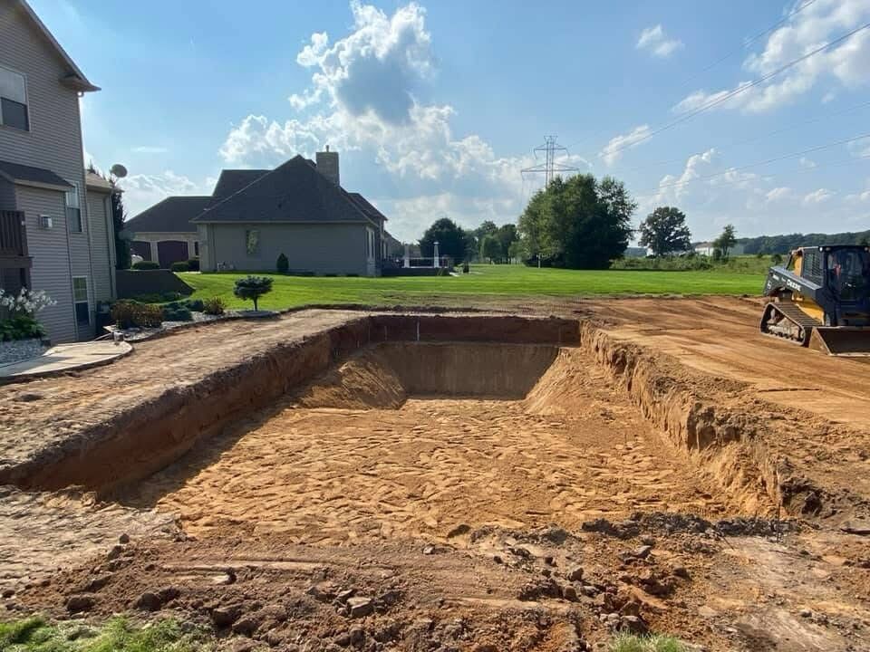 Excavated pool site graded and ready near a residential build
