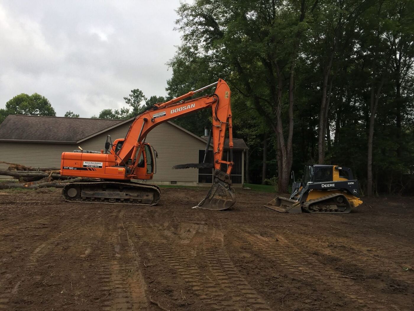 Excavator and skid steer clearing a residential lot