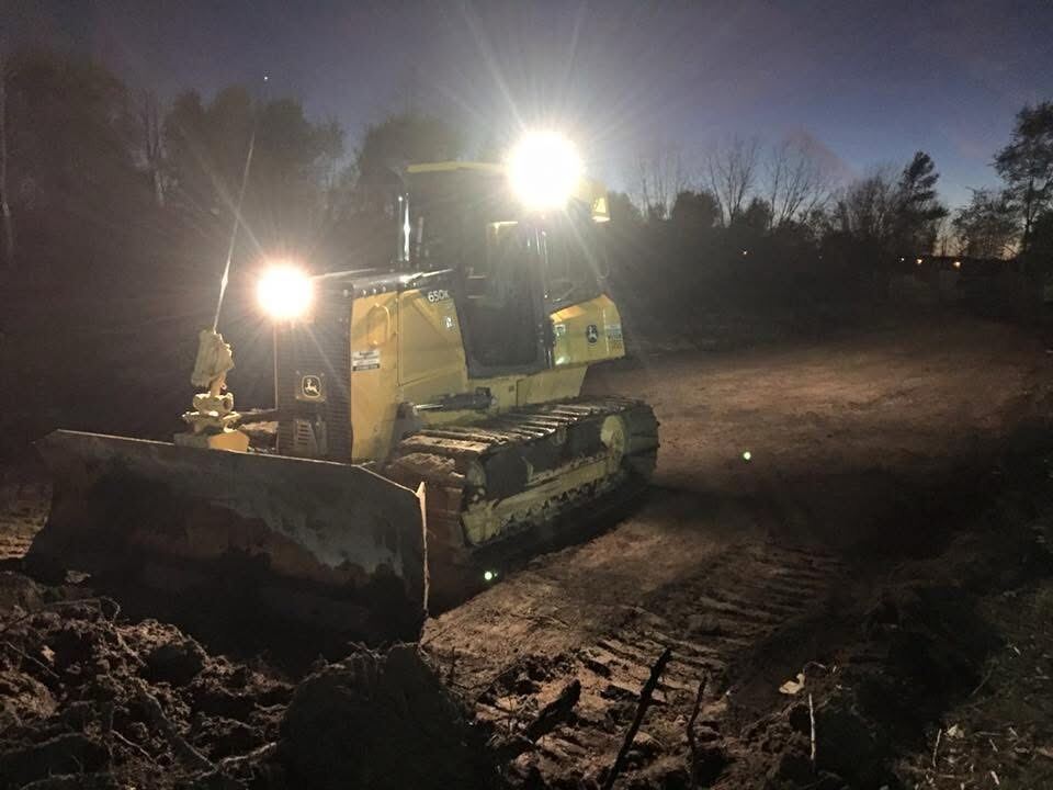 Dozer working a snow-covered job site after dark under floodlights